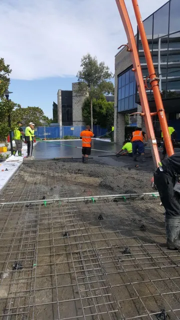 Crew placing concrete over steel reinforcement with a pump line