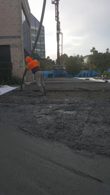 Concrete pump placing a slab next to a new building