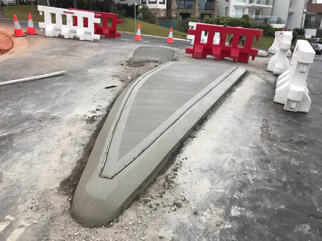 Newly poured concrete median island behind traffic barriers