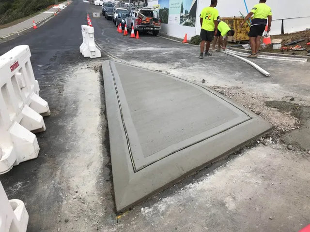Crew building a concrete median island on a live road